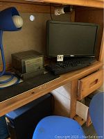 Dell desktop computer, monitor, keyboard on wooden desk with blue desk lamp and blue child's chair.