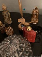 Close up of vintage filigree perfume bottles, red perfume bottle, bird pendant necklace with matching earrings on black surface