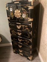 Full view of exterior front showing black lacquer finish, gold motifs and brass hardware