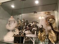 Glass cabinet display of assorted Jester and Harlequin dolls showing variations in costume and style.