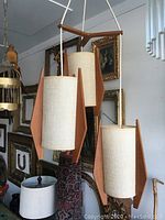 Full view of the fixture showing three cylindrical shades suspended from a teak frame