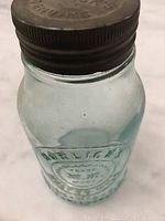 Front view showing blue-green tinted glass jar embossed with Horlick's Malted Milk.