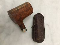 View of the wooden pipe bowl next to closed vintage leather pipe case.