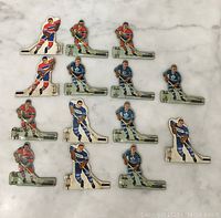 Full set of fourteen vintage metal hockey player figures arranged on a surface, showing various players and team jerseys.