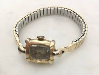 Angle showing front and band of vintage Omega ladies wristwatch in gold filled case with expandable band.