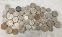 Overview of 40 assorted Franc coins arranged on white surface showing various sizes and finishes.