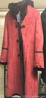 Red faux shearling coat with black faux fur collar, cuffs, and toggle closures, displayed on hanger with original tags visible.
