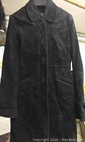 Full view of black leather coat showing button front, collar, and pockets.