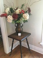 Corner view of small oak table with floral arrangement on top and brass claw feet with glass balls on legs.