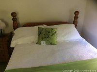 Front view of the pine four poster queen bed frame showing the headboard posts and bedding setup for scale.