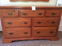 Frontal view of seven-drawer pine dresser against carpeted floor