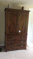 Front view of dark pine high boy dresser showing drawers and cabinet doors.