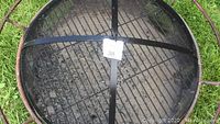 Top-down view of fire pit interior with mesh lid showing ash residue and grate