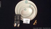 Photo showing three vintage Cataraqui Golf Club dishes, a pair of silver-plated decorative spoons, and a gold-tone golf bag shaped brooch.