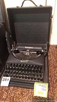 Frontal view of the vintage Remington Remette typewriter open in its black carry case, showing the keyboard and part of the carriage.