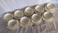 Nine Cream Colored Minton Lady Devonish Handled Soup Bowls with Matching Underplates Arranged in Rows