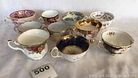 Side view showing various patterned tea cups including floral and gold trims