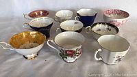 Top down view of ten assorted vintage tea cups showing floral and gold trim patterns