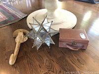 Photo showing all three items: glass star lantern, vintage leather case, and carved elephant wall shelf on wooden floor.