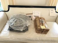 Light fixture and boxed parts placed on a cream couch, showing packaged items and instruction manual.