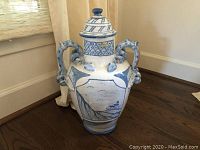 Front and side view of handpainted Italian covered vase with blue and white design, two handles, and a lid with knob top.