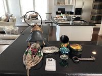 Overall display of all items on a black countertop in a kitchen setting including the purse sculpture, beaded purse, coin purse, key, and keepsake box.