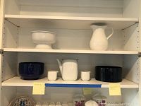 Shelving overview showing two cobalt blue bowls, white coffee pot and two creamers on middle shelf