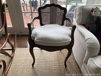 Front view of wooden caned armchair with cushion