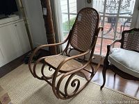 Angled view of bentwood rocker showing caned seat and back with scrolled rockers