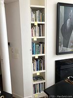 Tall bookshelf built into wall with a mix of books on interior design, gardening, and cooking.