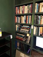 Full view of five-shelf bookcase containing mixed hardcover and paperback books