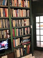 Full view of green bookshelf column with hardcover books