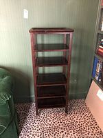 Front view of the tall wooden shelf unit showing its five shelves and dark finish