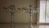 Pair of 5-arm cut glass crystal pendant candelabras, showing overall size and style against a wall.