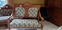 Front view of love seat showing ornate carved wood frame and floral brocade upholstery.