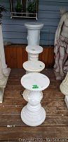 Four plaster pillar stands of varying heights and ornate design arranged in a row showing overall lot.