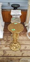 Four plaster plant stands: an ornate gold pedestal, a white chipped square pedestal, a small striped square pedestal, and a tall black round pedestal.