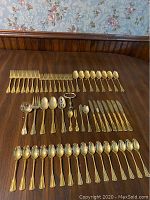 Overall view of all flatware laid out on table showing forks, spoons, knives, and serving pieces