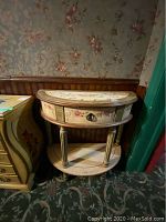 Full view of the wooden half-moon side table with painted floral decorations and a drawer, showing the lower shelf and legs.