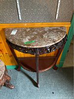Front view of semi-circular marble top side table with carved dark wood base.