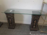 Full view of the glass top table with black and gold decorative pedestals under glass.