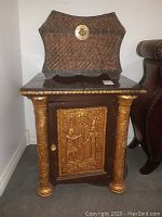 Front view of storage table showing Egyptian themed door and golden pillars.