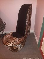 Chair in shape of high heel, showing front and main seating area with animal print upholstery and black inner seat fabric.