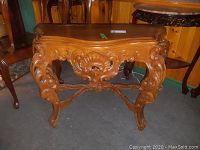 Front view of rectangular carved wood table showing apron and cabriole legs