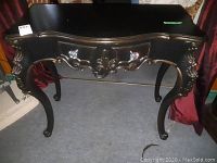 Front view of the black decorative wood table with curved edges and crystal-like drawer pulls.