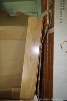 Single light oak plank leaning against open box