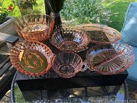 All six pink glass serving pieces displayed together outdoors on table