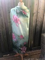 Scarf draped on mannequin showing full length and floral design in green and pink hues.