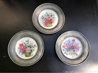 Three Kaiser West Germany decorative plates mounted in pewter frames, showing floral designs and ornate metalwork