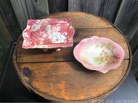 Both items shown on wooden surface: the covered dish with lid and the small hand-painted tray.